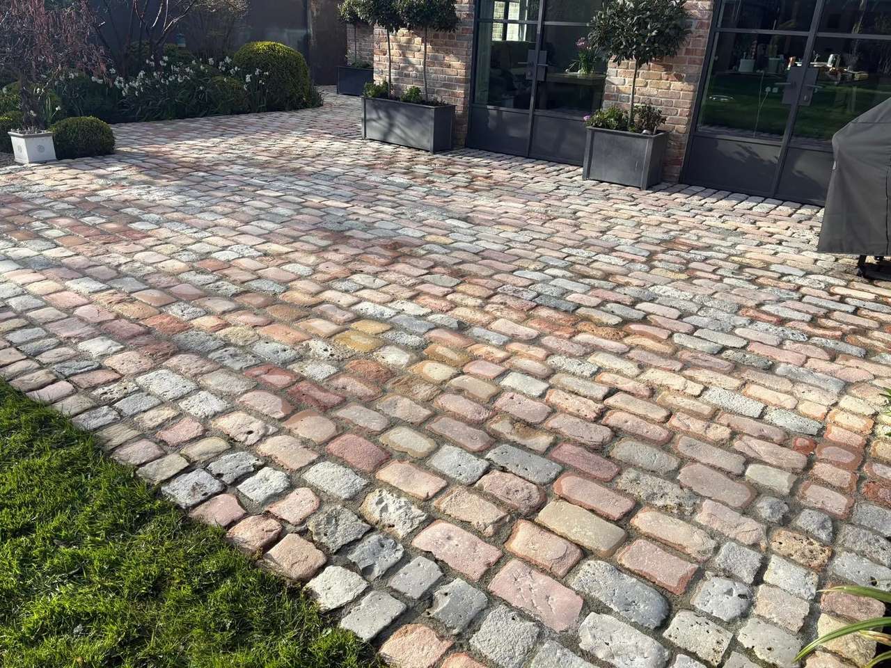 Reclaimed cobble patio pressure washed clean beside a brick house