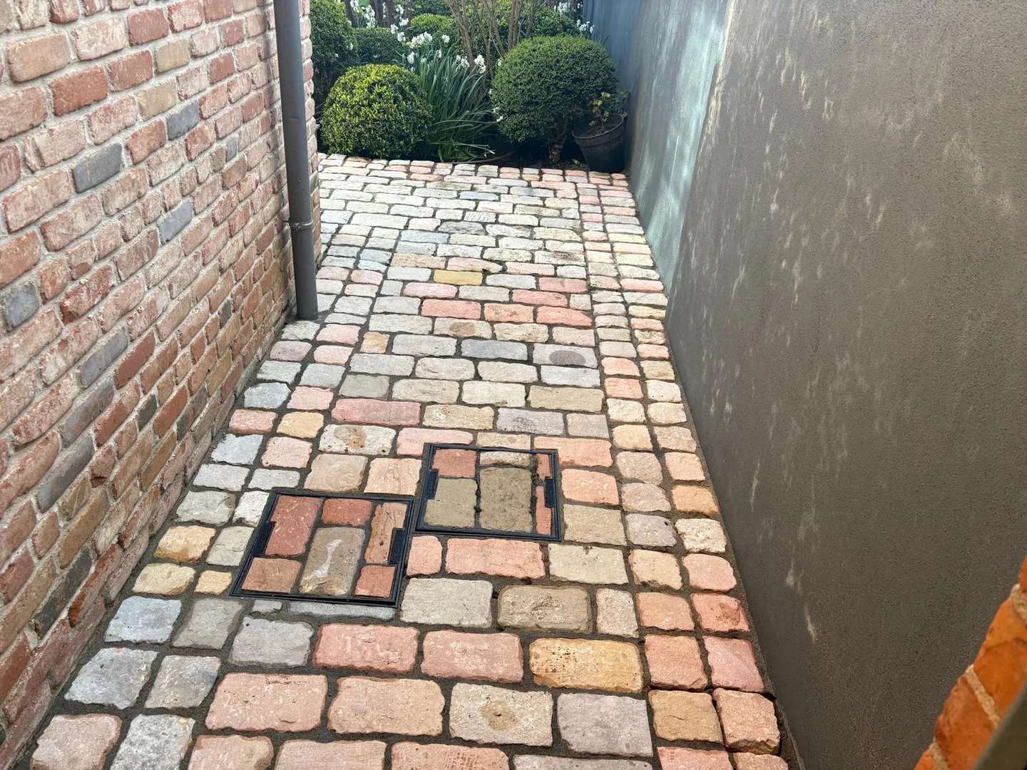 Cobbled side passage with drain covers after pressure washing
